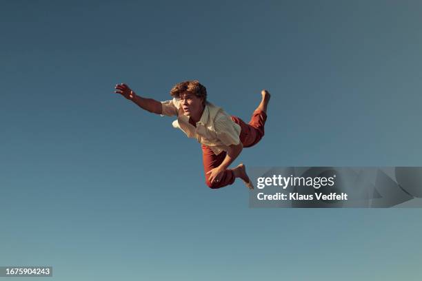 young man with hand raised flying in mid-air - man-falling-forward stock pictures, royalty-free photos & images