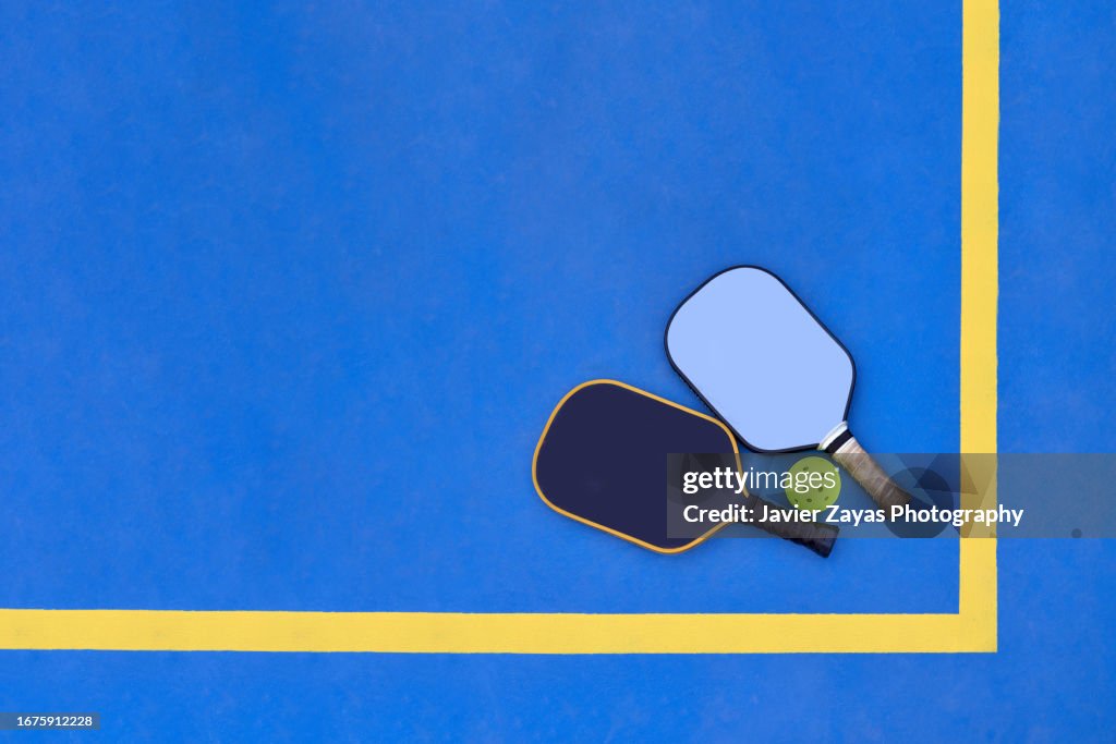 Two Pickleball Paddles and Ball on Pickle Ball Court