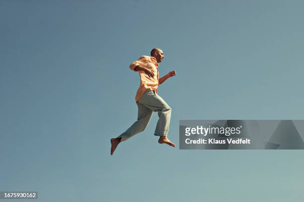 mature man walking in mid-air against clear blue sky - taking the plunge stock-fotos und bilder