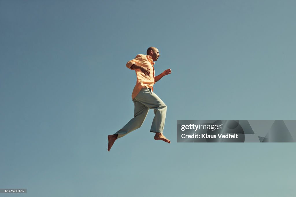 Mature man walking in mid-air against clear blue sky