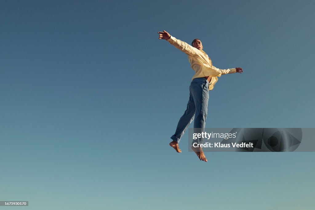 Young man jumping with arms outstretched