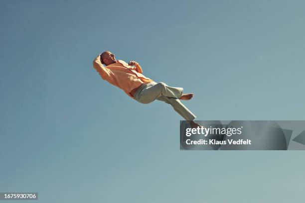 mature man levitating with leg cross - benen over elkaar geslagen stockfoto's en -beelden