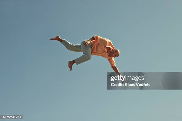 mature man jumping against clear blue sky - surrendering stock pictures, royalty-free photos & images