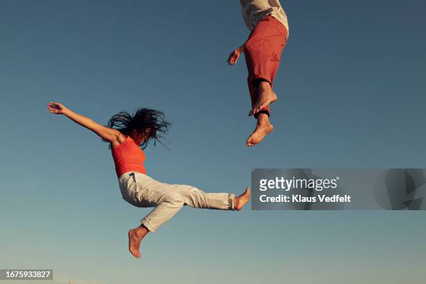 young friends jumping high up in mid-air while doing acrobat - change agility stock pictures, royalty-free photos & images