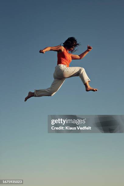 young woman doing acrobat high up in mid-air - frauenpower stock-fotos und bilder