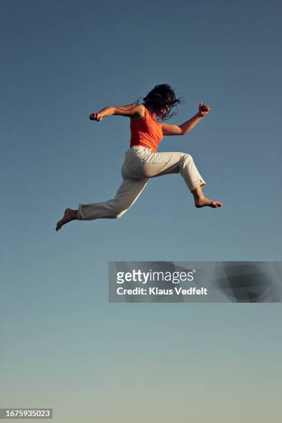 young woman doing acrobat high up in mid-air - leap forward stock pictures, royalty-free photos & images