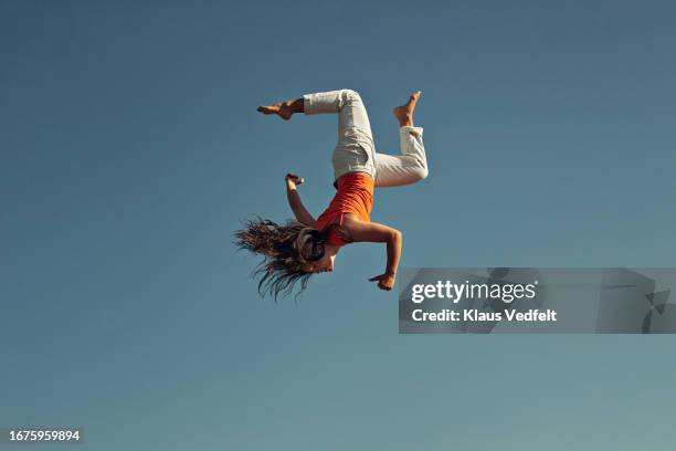 side view of young woman doing acrobat against clear blue sky - acrobate photos et images de collection