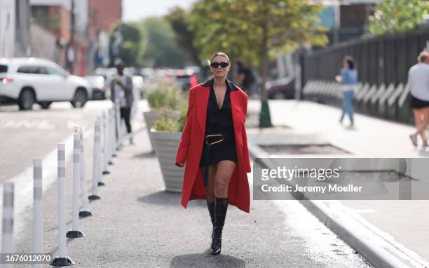 Veronica Ferraro was seen wearing earrings formed like red cherries, black Givenchy shades, a red coat, a black top with collar and a black belt with...