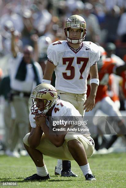 Kicker Xavier Beitia of Florida State eyes the kick as he squats on the field while holder Chance Gwaltney looks on against Miami during the game on...