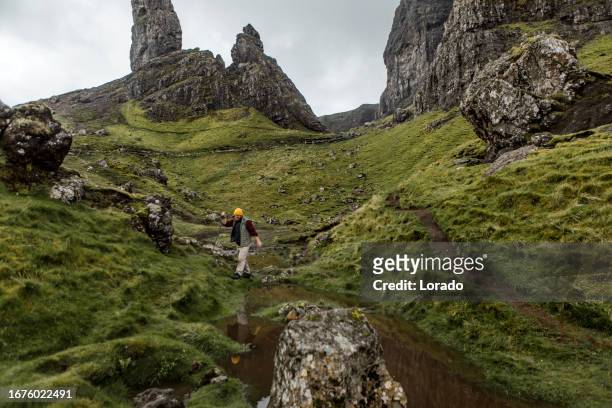 male hiker enjoying the freedom of the single life at the old man of storr in scotland - old man of storr stock pictures, royalty-free photos & images
