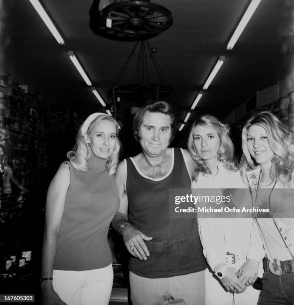 Country husband and wife singers Tammy Wynette and George Jones pose for a portrait with other customers at Nudie's Rodeo Tailor on May 26, 1973 in...