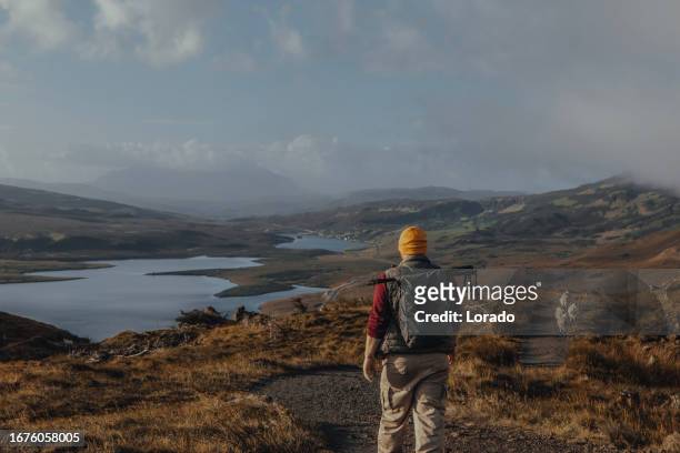 male hiker enjoying the beautiful countryside landscape of old man of storr - old man of storr stock pictures, royalty-free photos & images