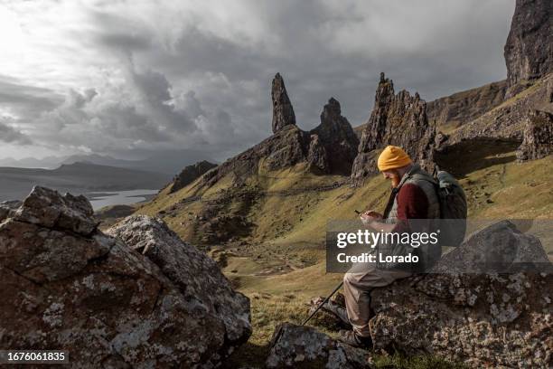 male hiker enjoying the beautiful countryside landscape of old man of storr - old man of storr stock pictures, royalty-free photos & images