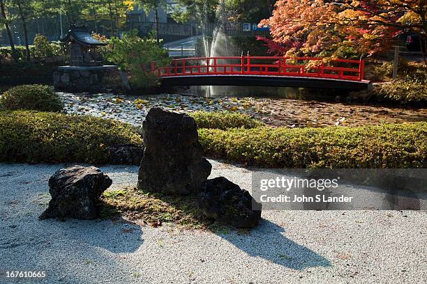 Zen Garden by the Lotus Pond at Garan, the sacred complex of temple buildings in Koyasan. The pond is crossed by a red bridge with a small island...