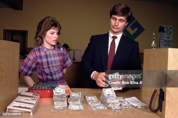 Federal Deposit Insurance Corporation Representative Doug Salo counts money from a bank tellers window from now insolvent Golden Valley Bank, March...