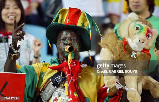 Supporter, clad in the Senegalese colors, holds up the mascot of the national team 'The Lions of Teranga' in the bleechers of Osaka Nagai Stadium,...