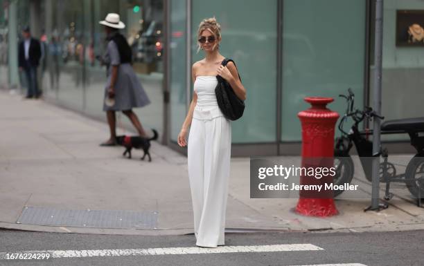 Xenia Adonts is seen outside Proenza Schouler show wearing black cat eye sunnies, silver drop earrings, a black leather Bottega Veneta Jodie shoulder...