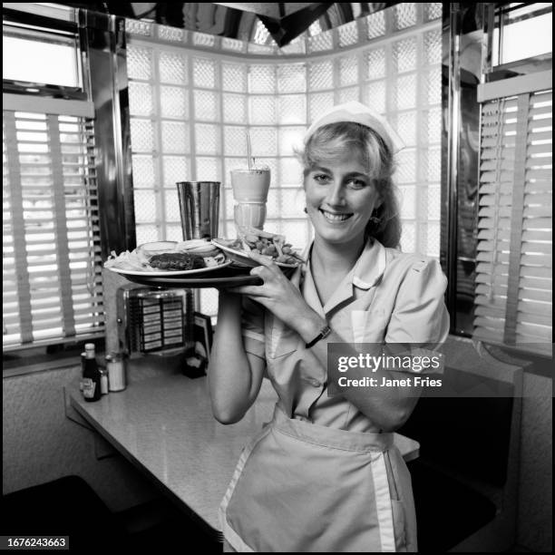 Portrait of waitress Dianne Booth as she poses with a tray of food at the American City Diner, Washington DC, August 1988.