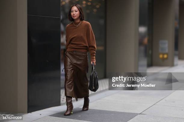 Aimee Song is seen outside Proenza Schouler show wearing golden Tiffany hardware necklace, brown wool pullover, brown leather skirt with matching...