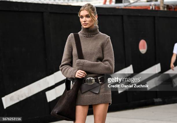 Elsa Hosk is seen wearing a brown knit sweater dress and black and silver belt with a brown bag outside the Michael Kors show during NYFW S/S 2024 on...