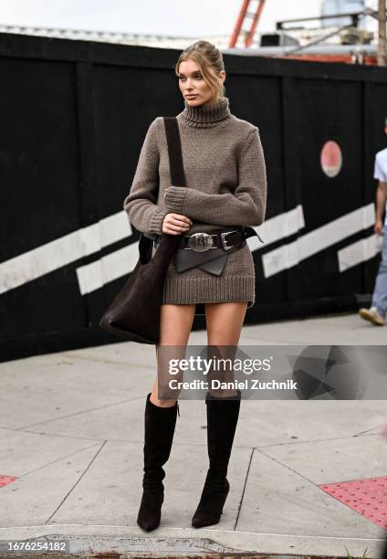 Elsa Hosk is seen wearing a brown knit sweater dress and black and silver belt with a brown bag and black boots outside the Michael Kors show during...