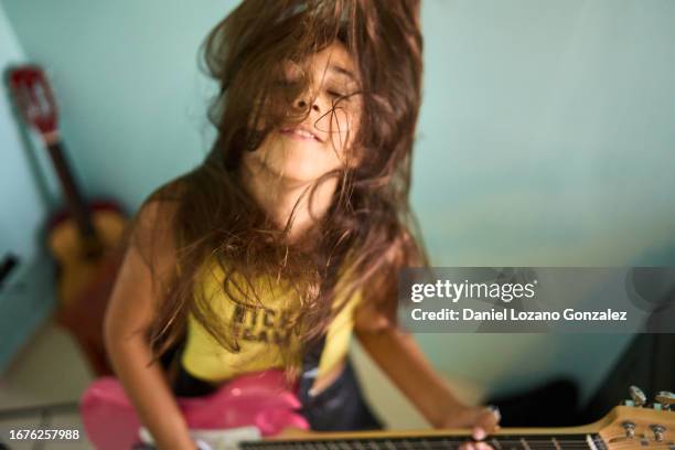 girl moving head while playing electric guitar in the bedroom - chitarra elettrica foto e immagini stock