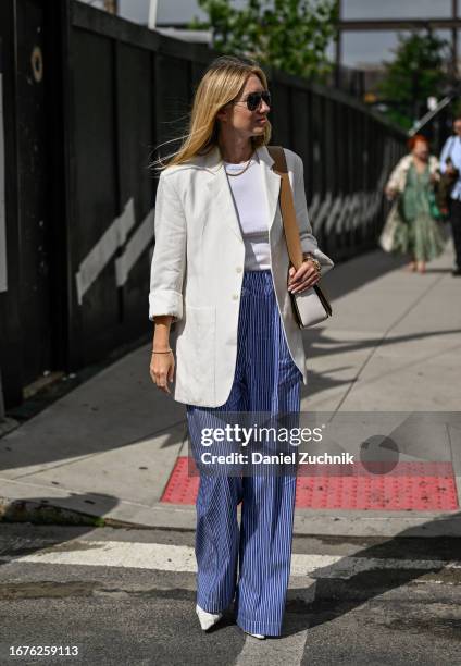 Lisa Aiken is seen wearing a white blazer, white top, blue and white striped pants and white shoes outside the Michael Kors show during NYFW S/S 2024...