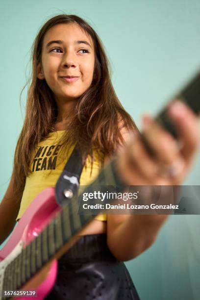 studio photo with blue background and low angle view of a cute girl playing an electric guitar - girl playing bass guitar fotografías e imágenes de stock