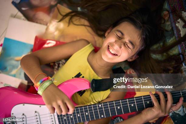 girl playing electric guitar lying on the bed - plucking an instrument stock pictures, royalty-free photos & images