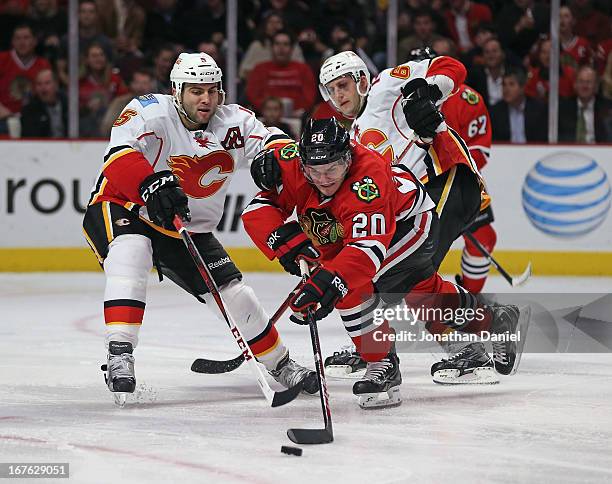 Brandon Saad of the Chicago Blackhawks tries to control the puck under pressure from Mark Giordano of the Calgary Flames at the United Center on...