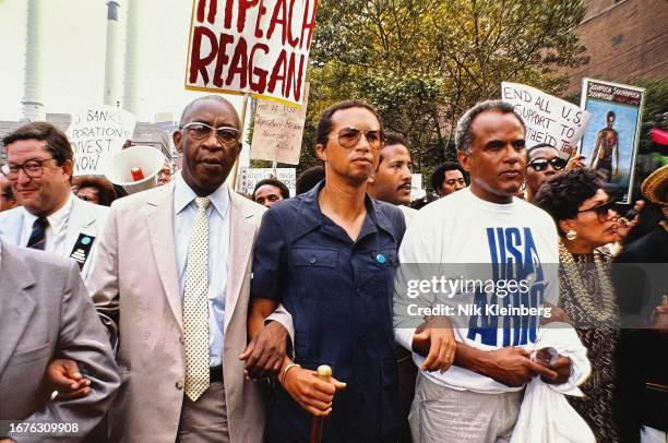 View of American tennis player Arthur Ashe and singer Harry Belafonte , among others, as they march during a demonstration outside the United...