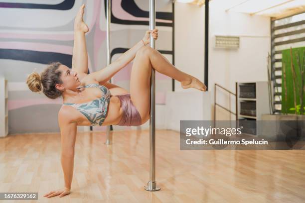 woman pole dancing, doing the flatline scorpio pose - pole dancing class stock pictures, royalty-free photos & images