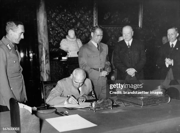 The official ceremony at City Hall in Hamburg. Reich Minister Wilhelm Frick signs into the Golden Book of the City of Hamburg. Behind him, the Reich...