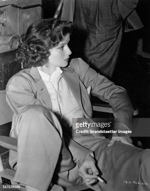 The actress Katharine Hepburn, sitting, dresses in suit. Photograph. About 1938. Die Schauspielerin Katharine Hepburn sitzend im Anzug. Photographie....