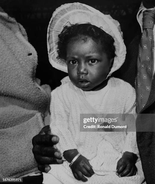 Brenda Lewis, 8 month old, wearing a bonnet, Waterloo station, London, August 23rd, 1957.