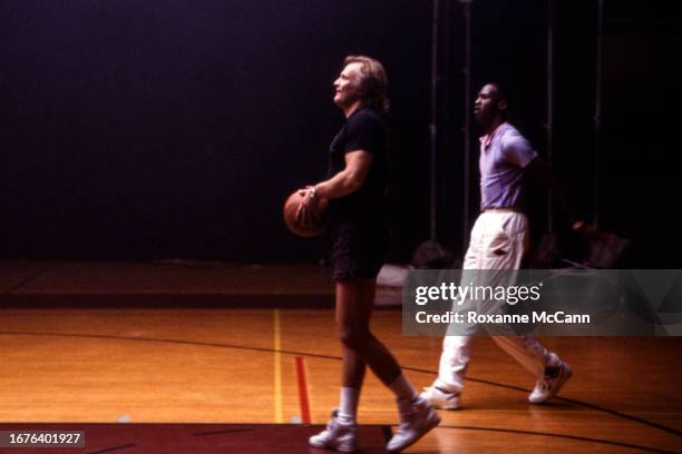 Director Joe Pytka gets ready to shoot a basketball while Michael Jordan of the Chicago Bulls watches, both wearing Nike shoes on the set of an Air...