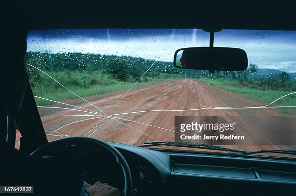 View through a cracked taxi windscreen on the lonely road between Koh Kong and Sre Ambel in Cambodia. For years, this road essentially did not exist,...