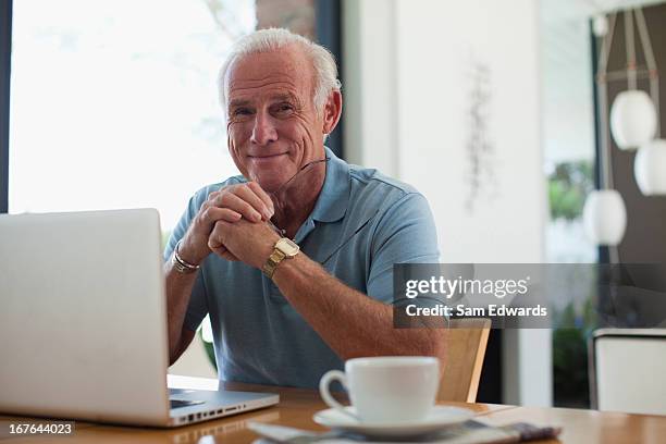 older man using laptop indoors - one senior man only stock pictures, royalty-free photos & images
