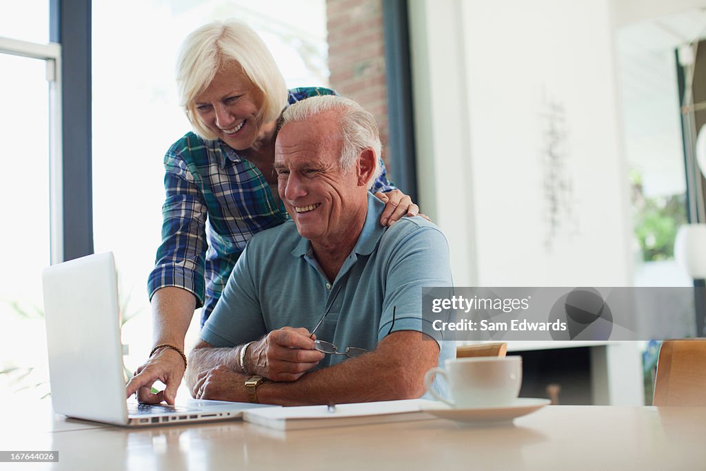 Sonriente Pareja de ancianos usando la computadora portátil juntos