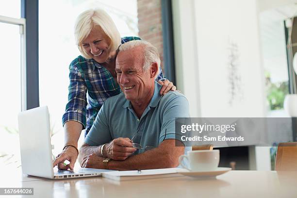 smiling older couple using laptop together - samuser stock pictures, royalty-free photos & images