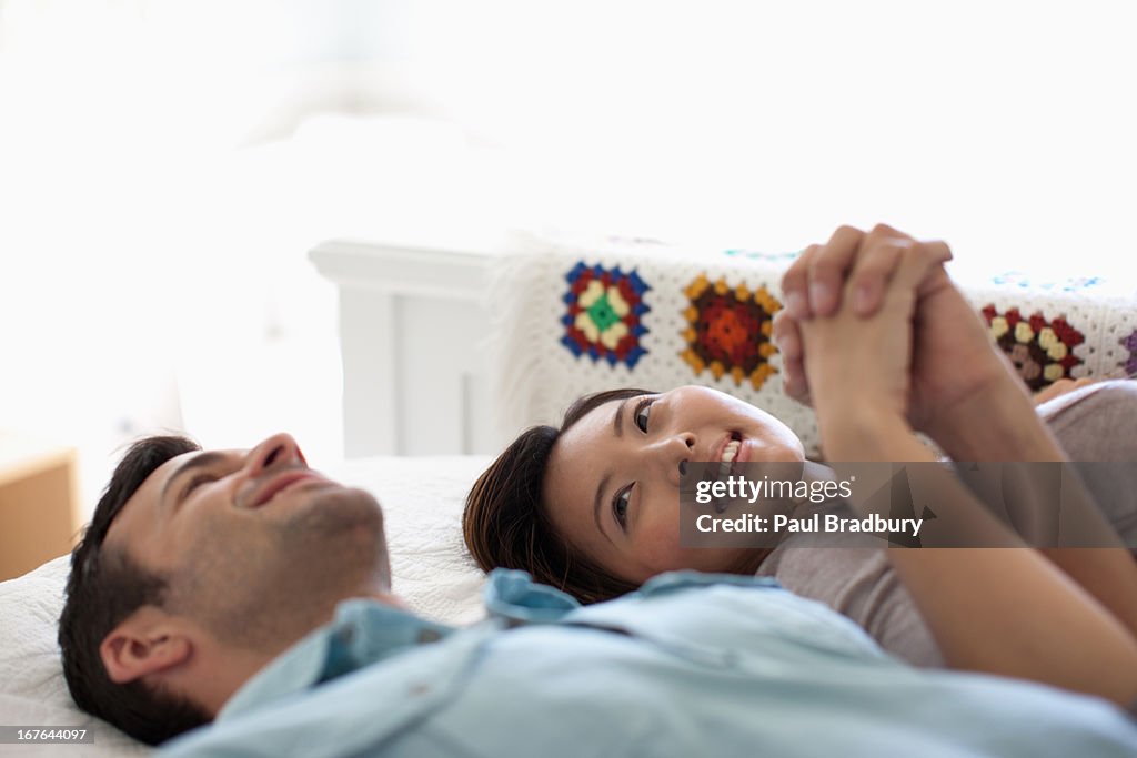 Smiling couple holding hands on bed