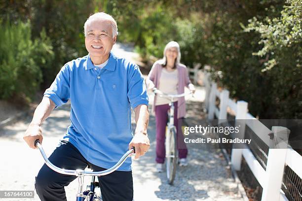 souriant couple de retraités équitation vélos - japanese mature women photos et images de collection