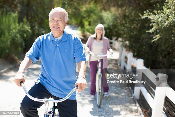 smiling older couple riding bicycles - asian exercise bildbanksfoton och bilder