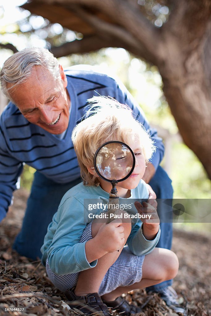 Older man and grandson using magnifying glass