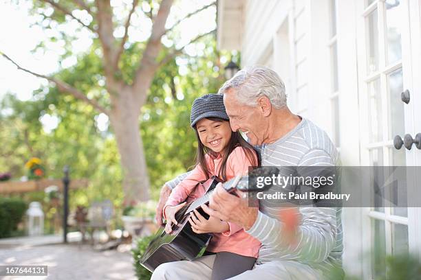 older man and granddaughter playing guitar - bradbury house stock pictures, royalty-free photos & images