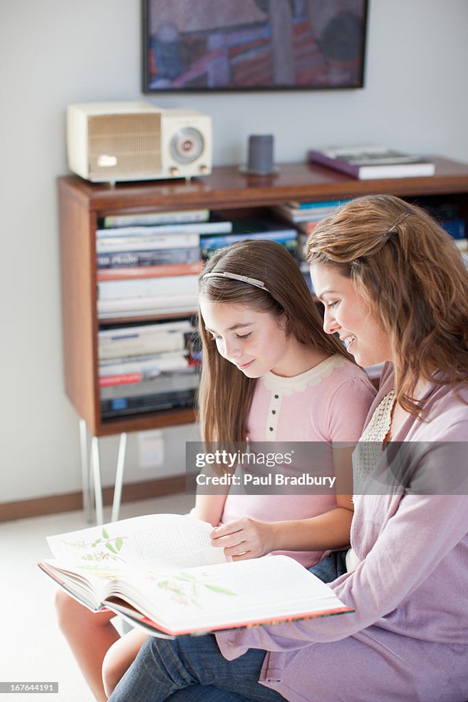 Mother and daughter reading together indoors