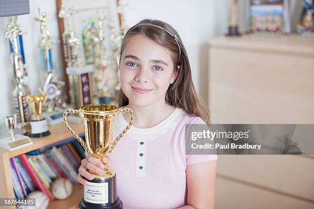 menina sorridente segurando troféu no quarto de dormir - title nine imagens e fotografias de stock