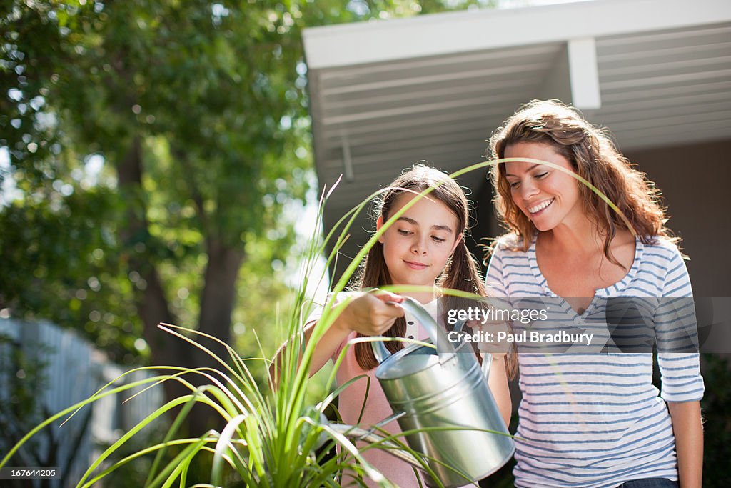 Mother and daughter watering plants outdoors