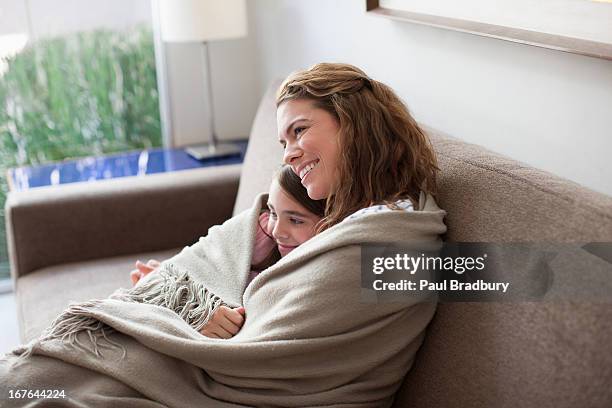 mère et fille sur le canapé emmitouflé dans une couverture - blanket photos et images de collection