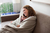 Mother and daughter wrapped in blanket on couch